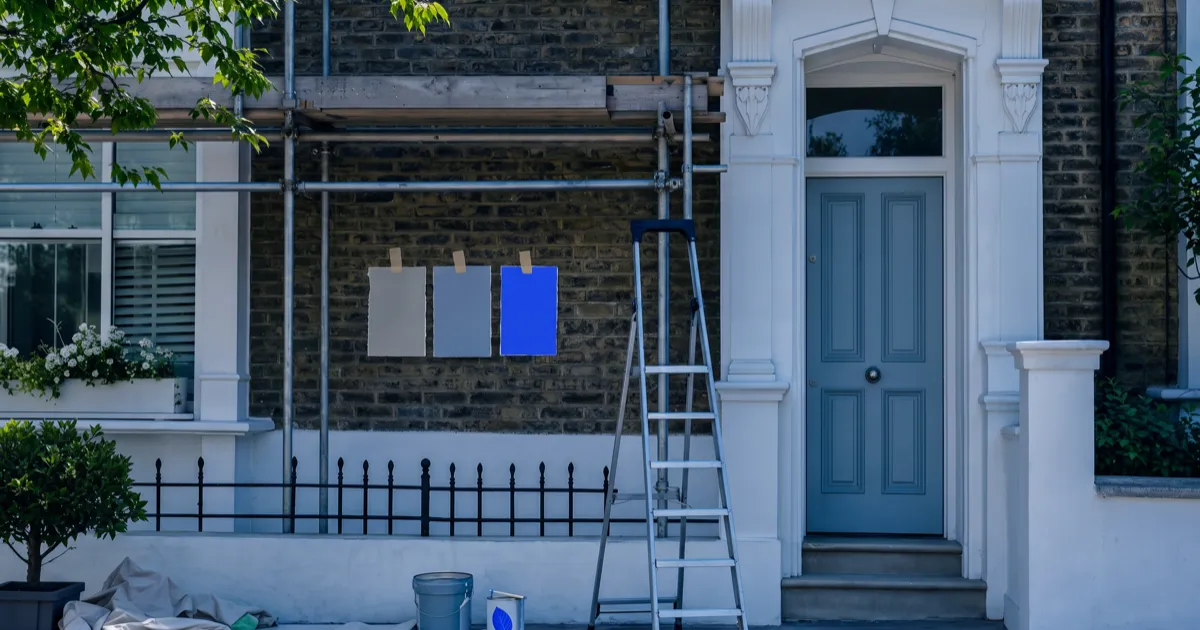 A terraced house under renovation with paint swatches, representing the website redesign cost and process in the UK